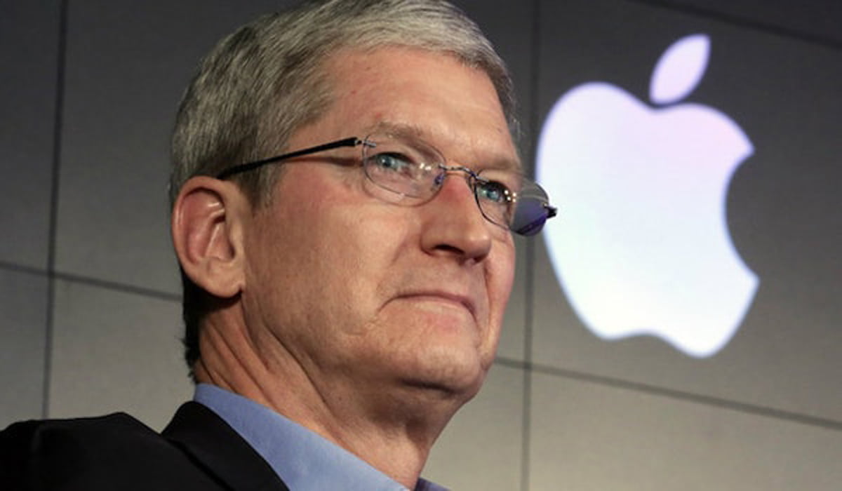 Apple CEO Tim Cook looks ahead, behind him the Apple logo
