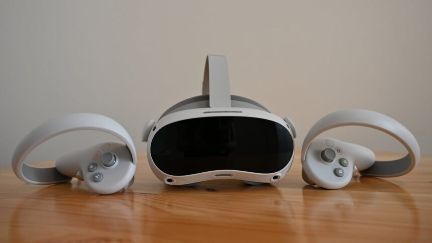 VR-Brille Pico 4 auf einem Tisch, von vorn, fankiert von den VR-Controllern 