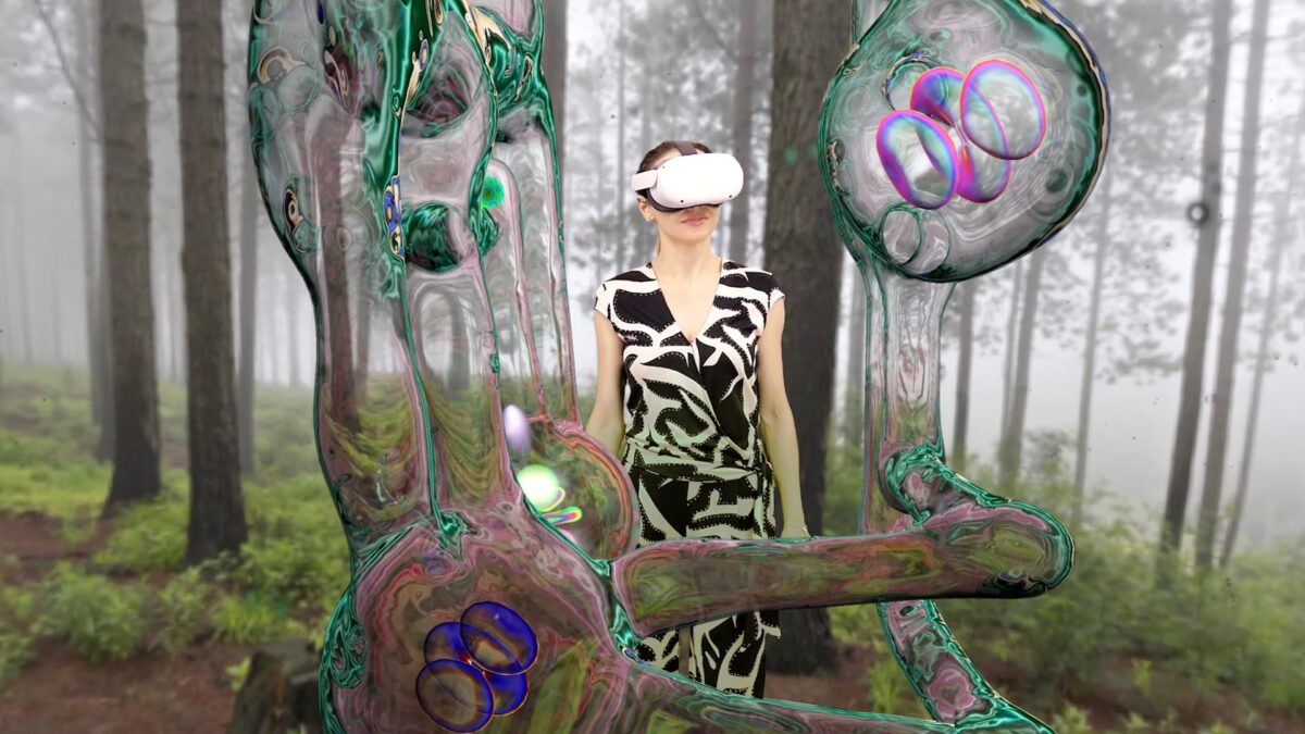 A woman with Quest stands in a virtual forest, with an organic Squingle entity in front of her.