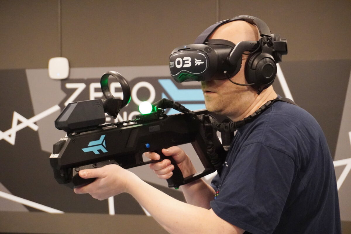 Mixed author Jan Wöbbeking wears a Vive Focus 3, headphones and a weapon controller in the VR arcade Zero Latency.