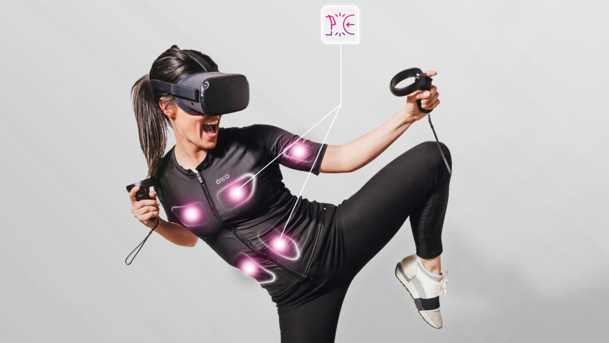 A woman in an athletic kicking pose feels electric shocks on electrodes of the haptic Owo vest.