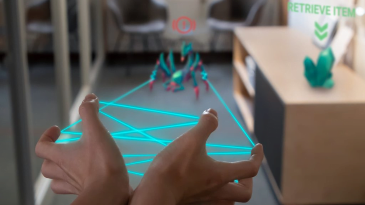 An augmented reality image shows the hands in front of the user in focus and a mechanics scorpion in the distance out of focus.