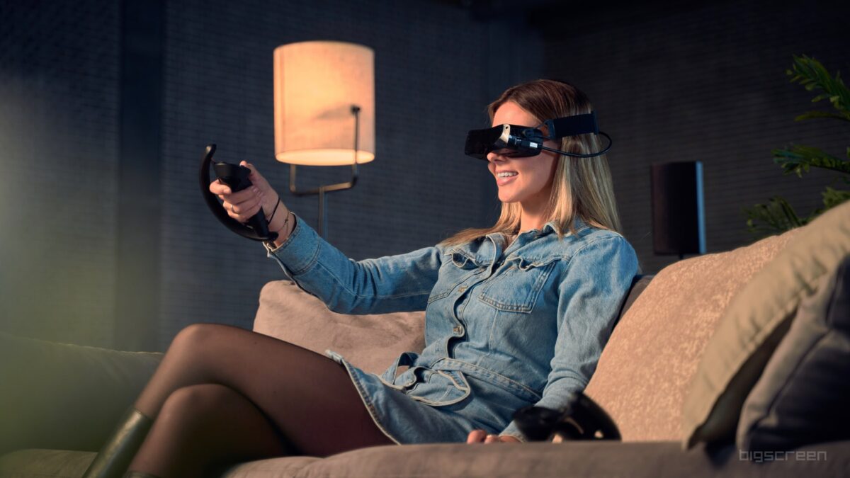 Bigscreen Beyond VR headset worn by a woman sitting on a couch.