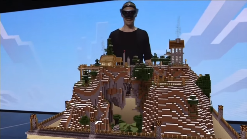 A guy with Hololens on his head projecting a Minecraft 3D scene on a table. It's a scene from Microsoft's E3 2015 press conference where they demonstrated Hololens 1 as a gaming device.