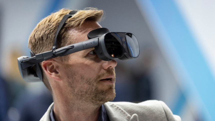 Een beursbezoeker probeert met een verbaasde blik het nieuwe frontpaneel van de Vive XR Elite VR-headset uit.