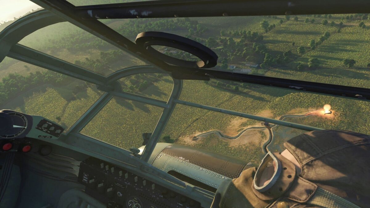 View into the cockpit of a pilot. Below him a green landscape with trees.