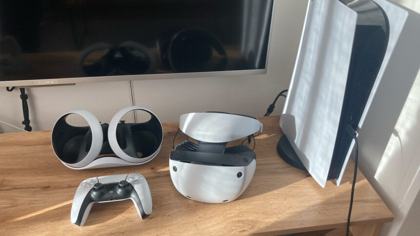 On a cabinet, PS5, PSVR 2, a Dualsense controller and the Sense controller charging station are placed next to each other.