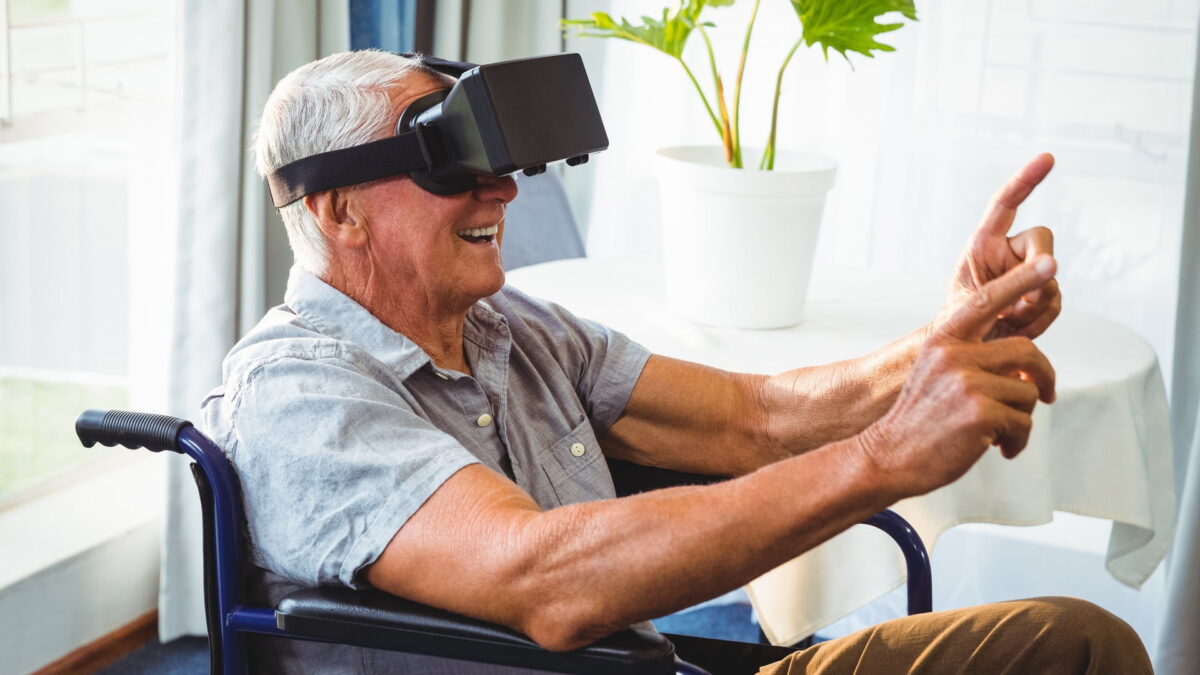 Senior in wheelchair wearing VR headset smiles because of VR experience