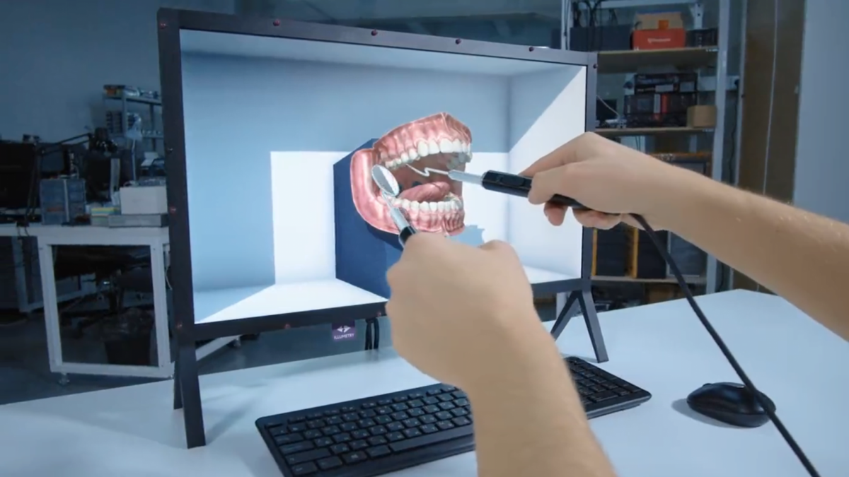 A dentist views a spatial denture model on Illumetry IO's XR monitor from a first-person perspective, with instruments held in front of it.