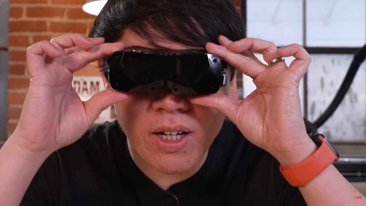 Norman Chan of Adam Savage's Tested holds the Bigscreen Beyond headset against his face.