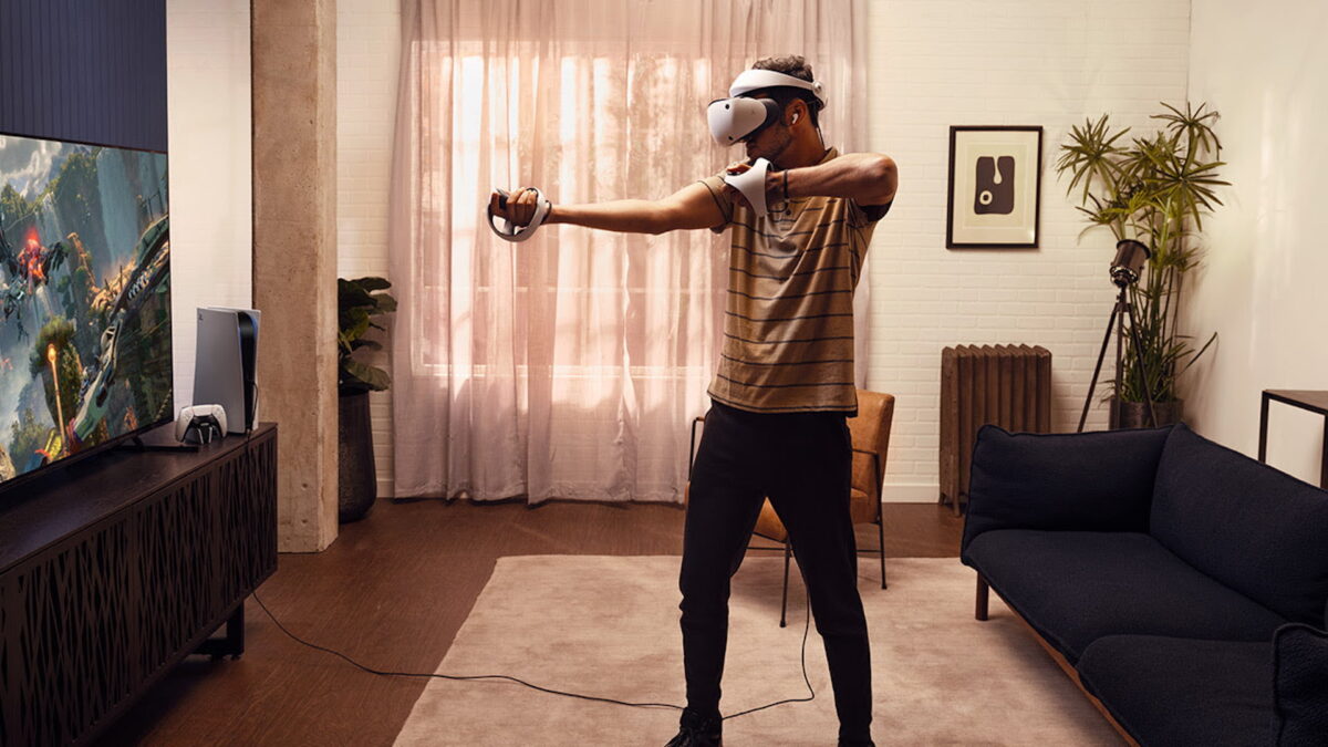 거실에서 Playstation VR 2를 가지고 노는 청년.