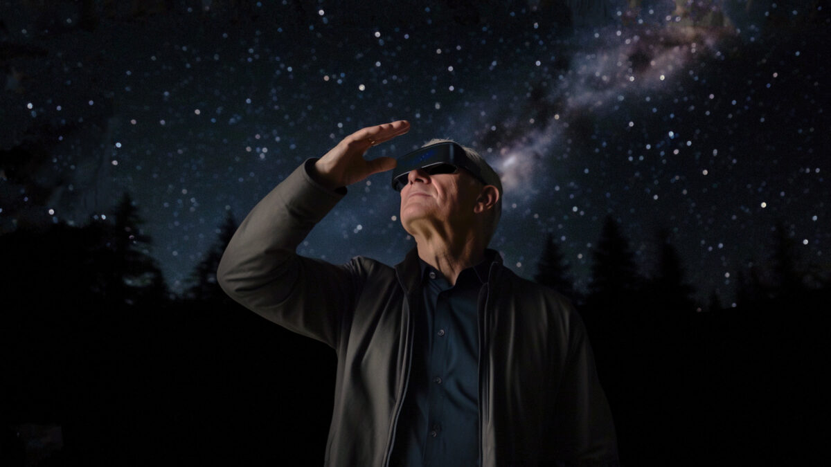 Tim Cook wears an XR headset, with the Milky Way and stars behind.