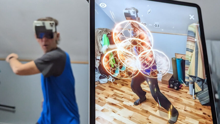 A person wears a HoloKit X while an iPad in the foreground reveals the augmented view he sees.