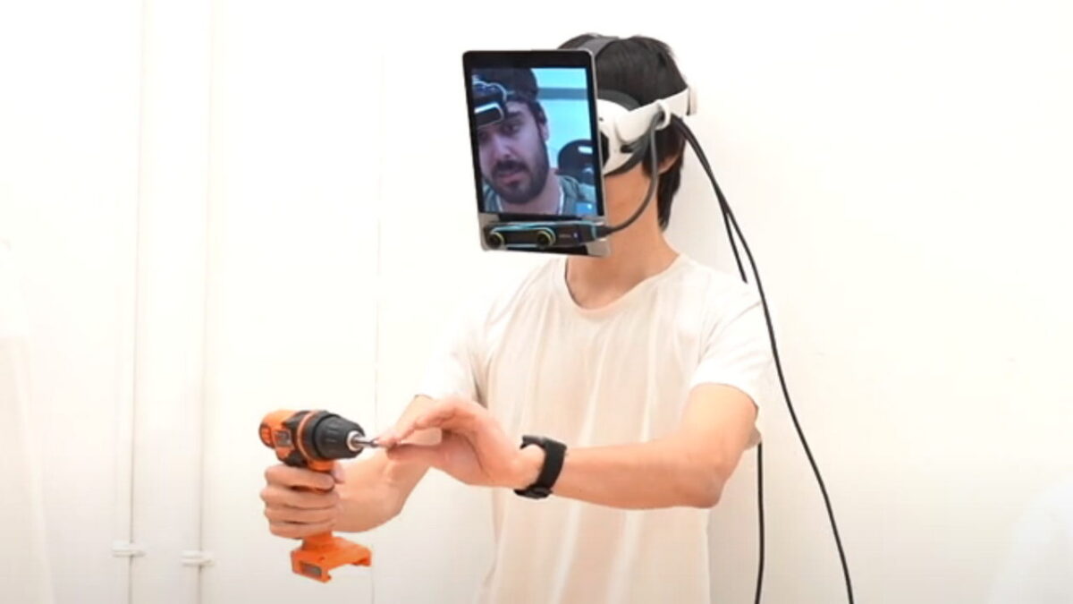 A man screws together a component while wearing a tablet and VR headset construction on his face.