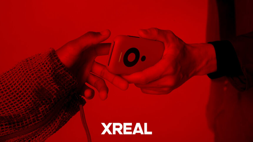 A closeup of someone being handed an Xreal Beam in shades of red.