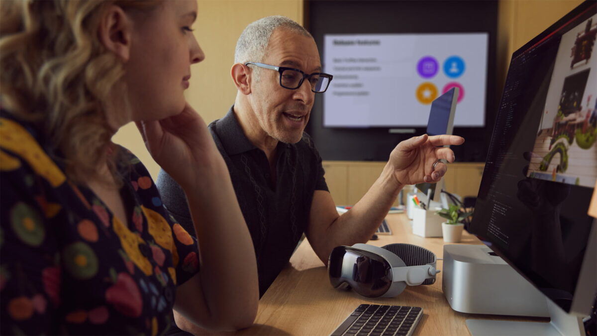 Two developers in front of the Apple Vision Pro SDK on multiple monitors.