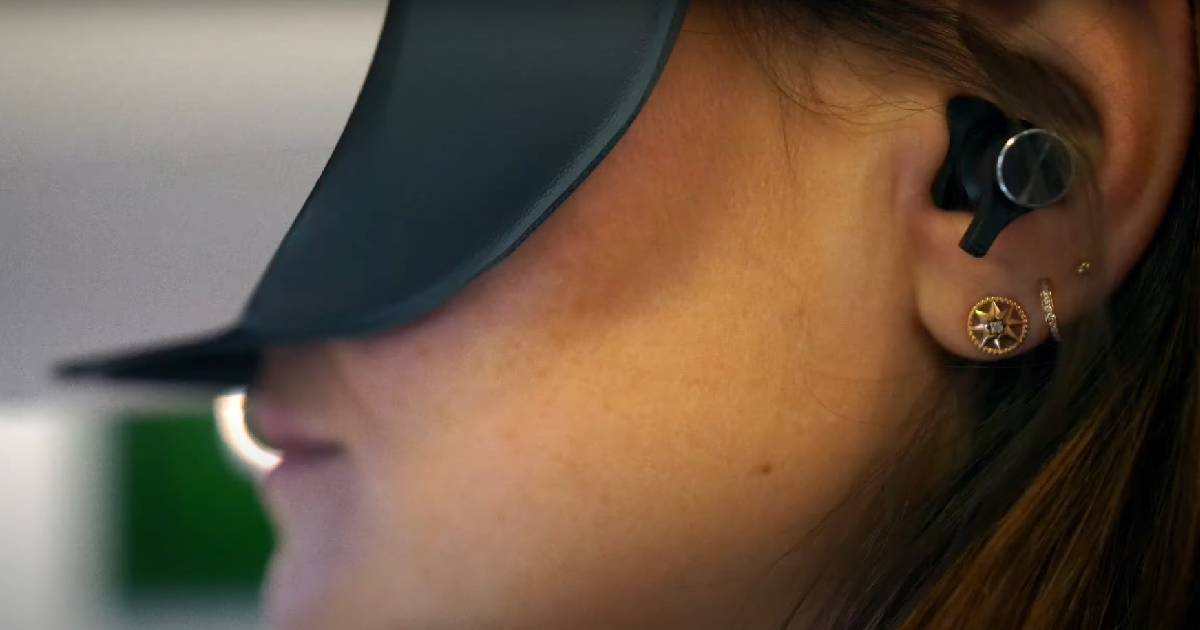 Side view of a woman wearing VR headset and an in-ear headset.