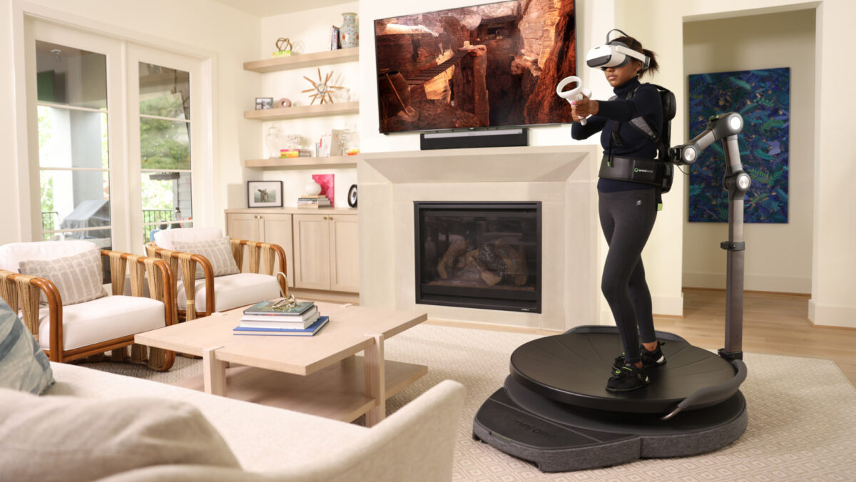 A young woman on the VR treadmill Virtuix Omni One standing in the living room.