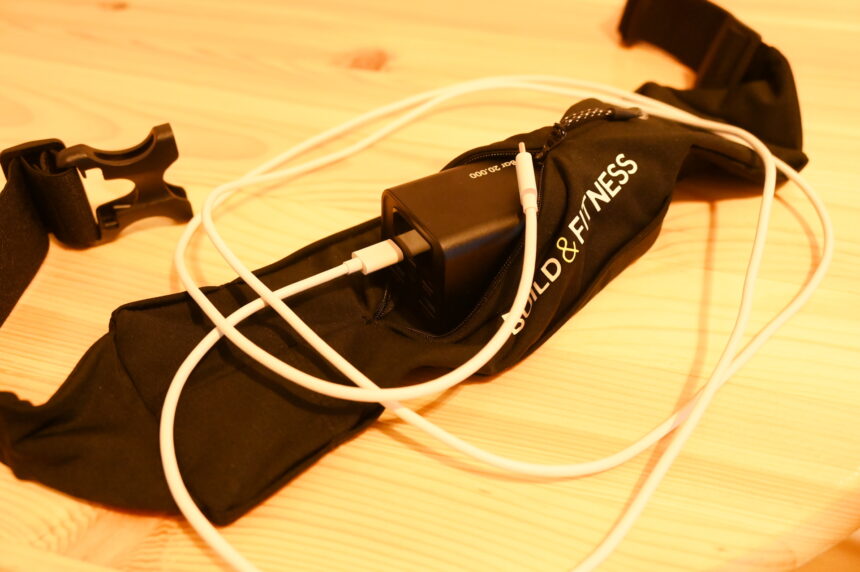 Sports belt with power bank and white UB-C cable on a table.