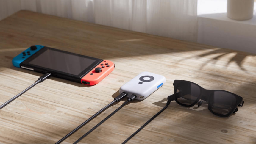 A Nintendo Switch, an Xreal Beam and the Xreal Air 2 headset lie on a wooden table and are connected via USB-C cable.