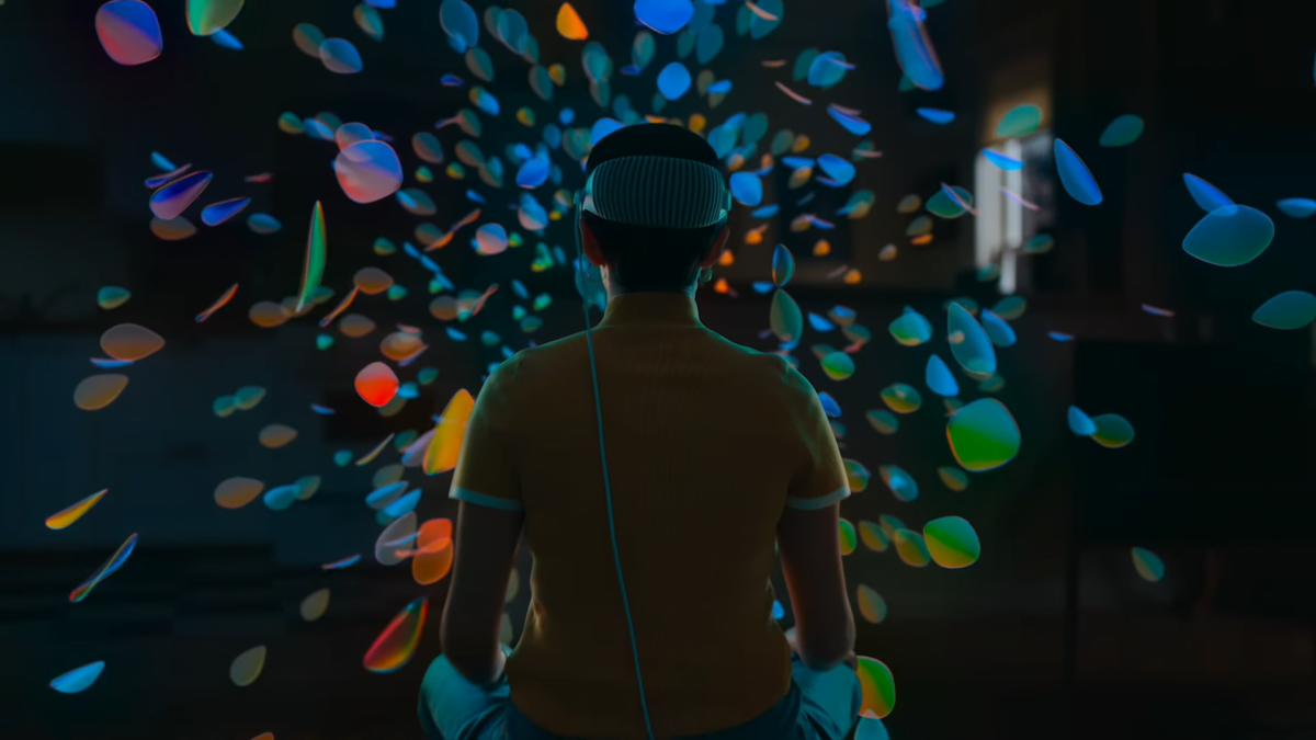 A man with an Apple Vision Pro on his head is in virtual reality, surrounded by bright colors.