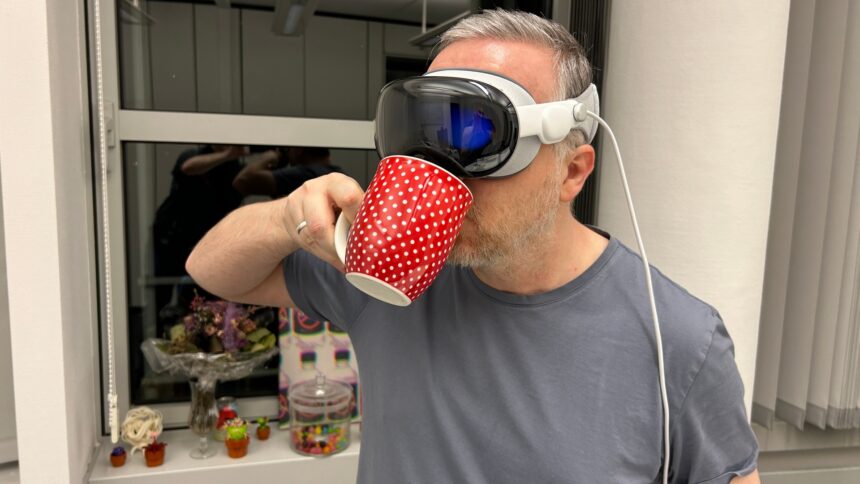 Man with Apple Vision Pro on his head drinks from a coffee cup