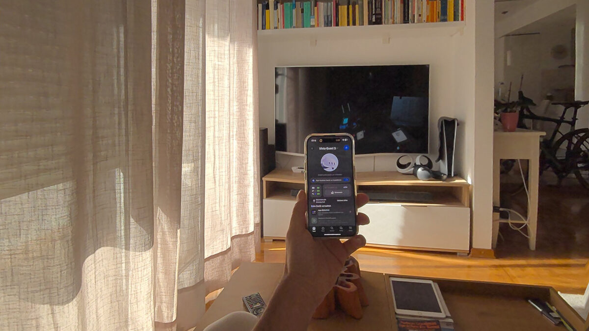 Passthrough view of a living room with Quest Update 64. The user holds a smartphone in front of him.