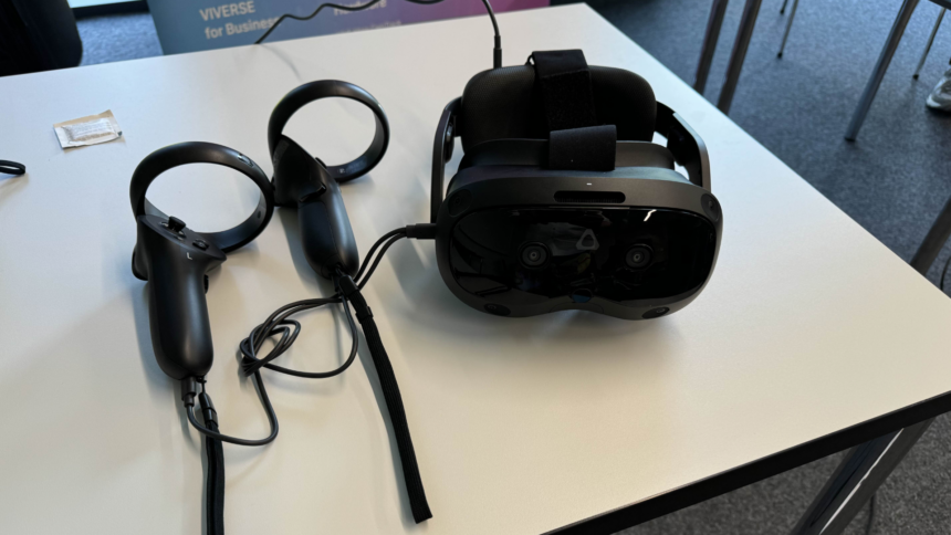 The HTC Vive Focus Vision VR headset and two VR controllers lie on a white table.