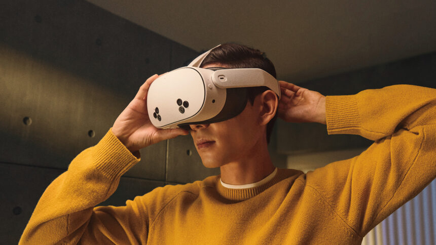 A man in a yellow sweater pulls the Meta Quest 3S VR headset over his head.